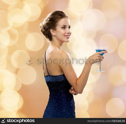 party, drinks, holidays, luxury and celebration concept - smiling woman in evening dress holding cocktail over beige lights background