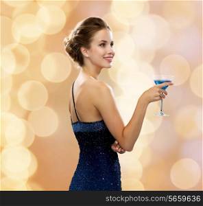 party, drinks, holidays, luxury and celebration concept - smiling woman in evening dress holding cocktail over beige lights background