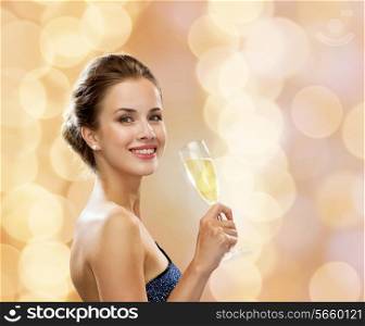 party, drinks, holidays, luxury and celebration concept - smiling woman in evening dress with glass of sparkling wine over beige lights background
