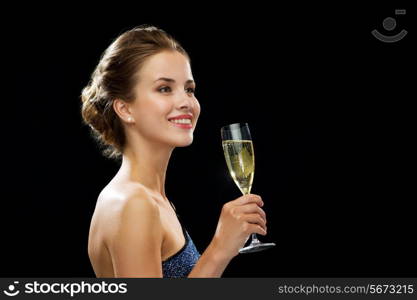 party, drinks, holidays, luxury and celebration concept - smiling woman in evening dress with glass of sparkling wine over black background