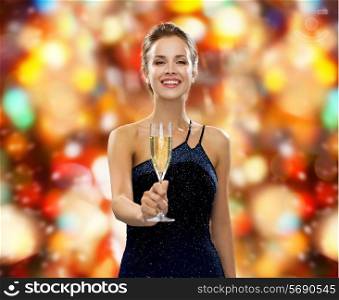 party, drinks, holidays, luxury and celebration concept - smiling woman in evening dress with glass of sparkling wine over red lights background