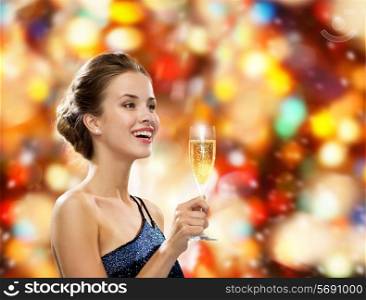 party, drinks, holidays, luxury and celebration concept - smiling woman in evening dress with glass of sparkling wine over red lights background