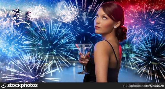 party, drinks, holidays, luxury and celebration concept - smiling woman in evening dress holding cocktail over nigh city and firework background