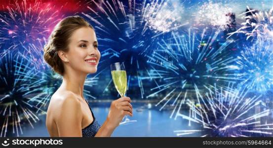 party, drinks, holidays, luxury and celebration concept - smiling woman in evening dress with glass of sparkling wine over nigh city and firework background