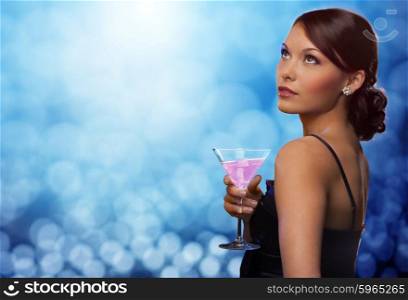 party, drinks, holidays, luxury and celebration concept - smiling woman in evening dress holding cocktail over blue lights background