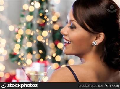 party, drinks, holidays, luxury and celebration concept - woman face with cocktail over christmas tree lights