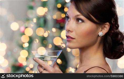 party, drinks, holidays, luxury and celebration concept - woman face with cocktail over christmas tree lights