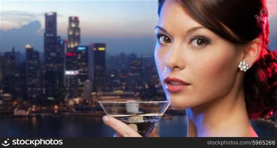party, drinks, holidays, luxury and celebration concept - woman holding cocktail over singapore night city background