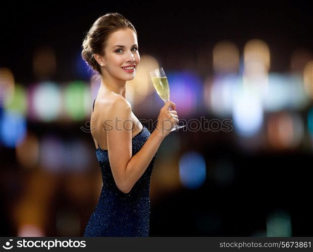 party, drinks, holidays, people and celebration concept - smiling woman in evening dress with glass of sparkling wine over night lights background