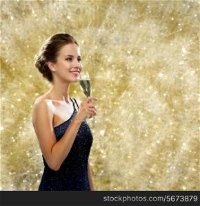 party, drinks, holidays, people and celebration concept - smiling woman in evening dress with glass of sparkling wine over yellow lights background