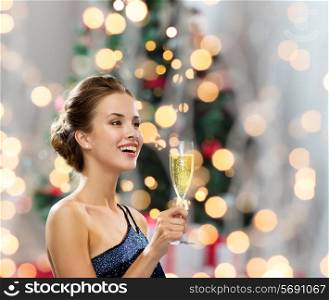 party, drinks, holidays, people and celebration concept - smiling woman in evening dress with glass of sparkling wine over christmas tree lights background