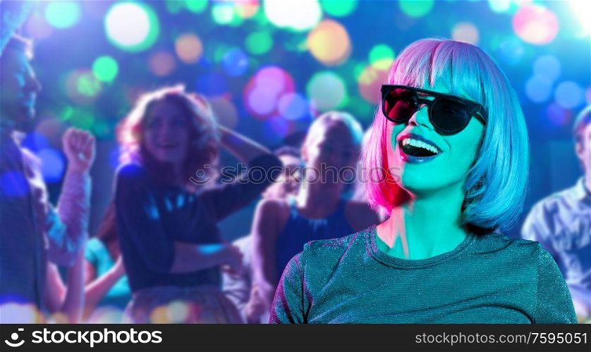 party, fashion and people concept - happy young woman in pink wig and black sunglasses over people dancing at nightclub background. happy woman in pink wig and sunglasses at party