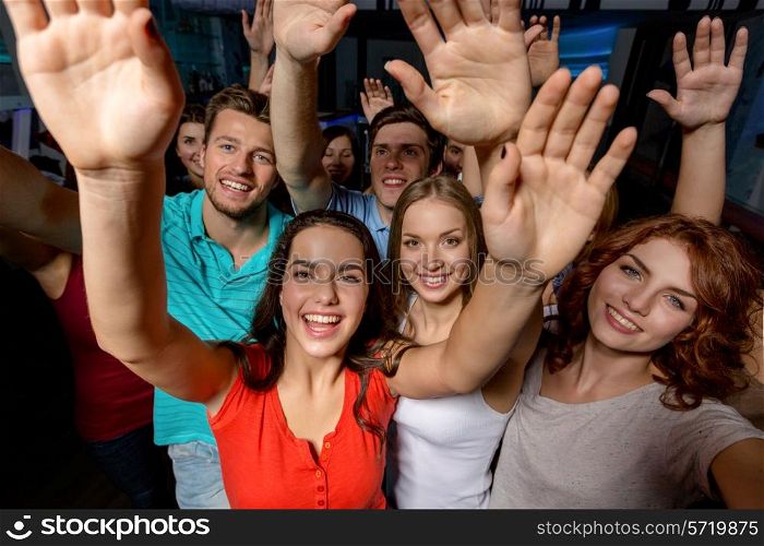 party, holidays, celebration, friends and people concept - smiling friends dancing and waving hands in club