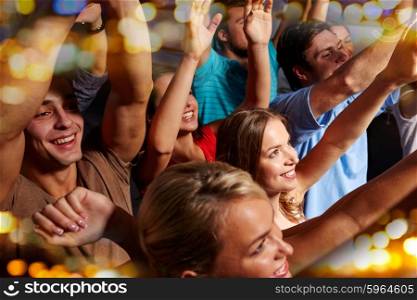 party, holidays, celebration, nightlife and people concept - group of smiling friends waving hands at concert in club