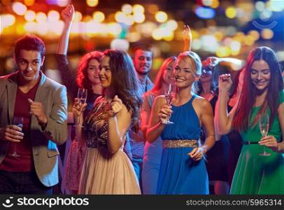 party, holidays, celebration, nightlife and people concept - happy friends with glasses of non-alcoholic champagne dancing at disco in nightclub