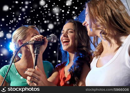 party, holidays, celebration, nightlife and people concept - happy young women singing karaoke in night club and snow effect