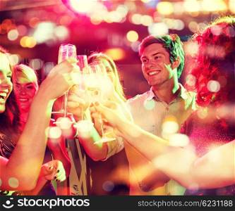 party, holidays, celebration, nightlife and people concept - smiling friends clinking glasses of champagne in club