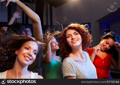 party, holidays, celebration, nightlife and people concept - smiling friends dancing at concert in club