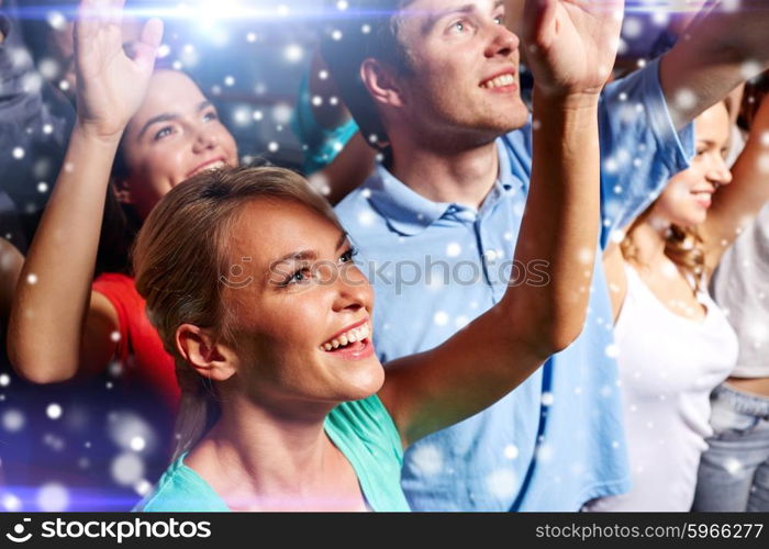 party, holidays, celebration, nightlife and people concept - smiling friends waving hands at concert in club and snow effect