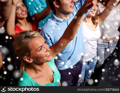 party, holidays, celebration, nightlife and people concept - smiling friends waving hands at concert in club and snow effect