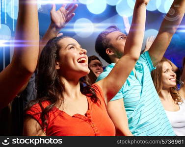 party, holidays, celebration, nightlife and people concept - smiling friends waving hands at concert in club