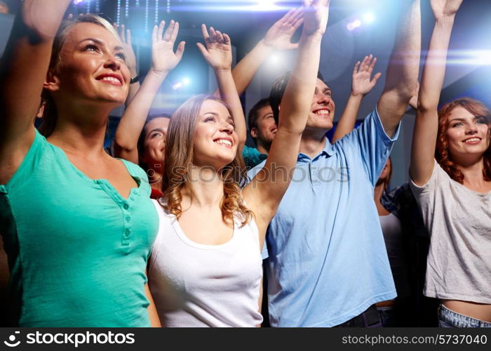 party, holidays, celebration, nightlife and people concept - smiling friends waving hands at concert in club