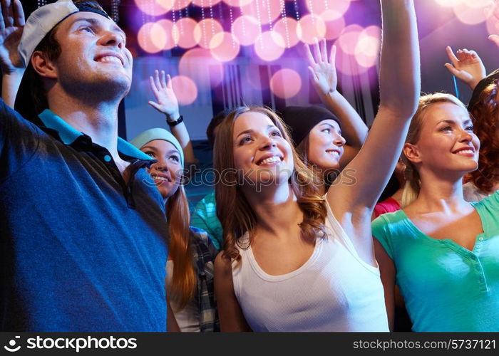 party, holidays, celebration, nightlife and people concept - smiling friends waving hands at concert in club