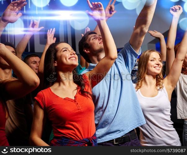 party, holidays, celebration, nightlife and people concept - smiling friends waving hands at concert in club