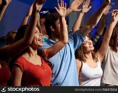 party, holidays, celebration, nightlife and people concept - smiling friends waving hands at concert in club