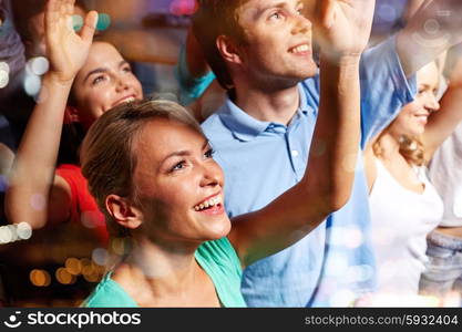 party, holidays, celebration, nightlife and people concept - smiling friends waving hands at concert in club