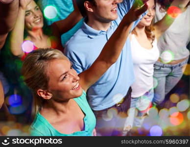 party, holidays, celebration, nightlife and people concept - smiling friends waving hands at concert in club