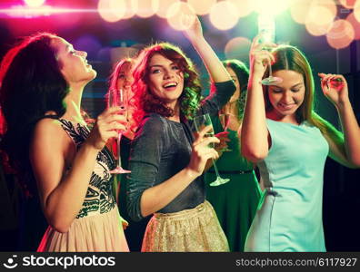 party, holidays, celebration, nightlife and people concept - smiling friends with glasses of champagne dancing in club