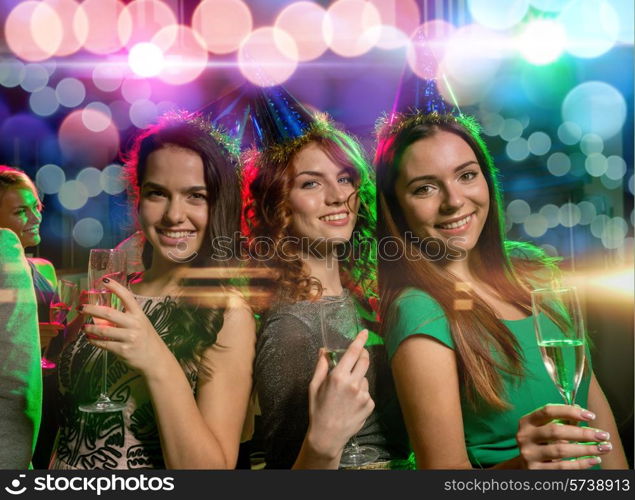 party, holidays, celebration, nightlife and people concept - smiling friends with glasses of champagne in club