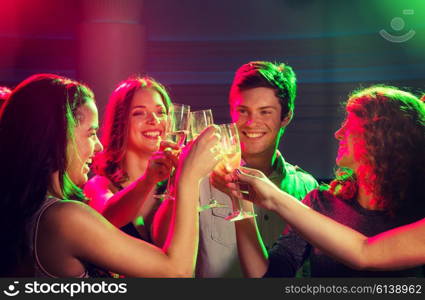 party, holidays, celebration, nightlife and people concept - smiling friends with glasses of champagne in club