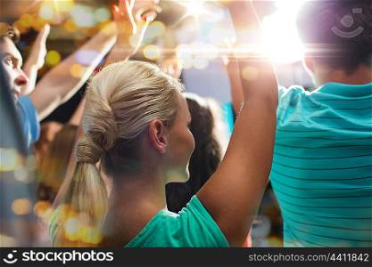 party, holidays, music, nightlife and people concept - close up of happy people at concert in night club waving hands
