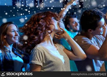 party, holidays, nightlife and people concept - happy friends dancing at night club and snow effect