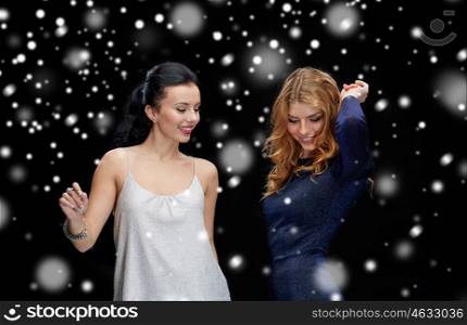 party, holidays, nightlife and people concept - happy young women dancing at night club disco over black background
