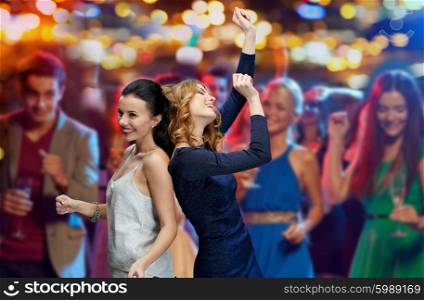 party, holidays, nightlife and people concept - happy young women dancing at night club disco over night lights background
