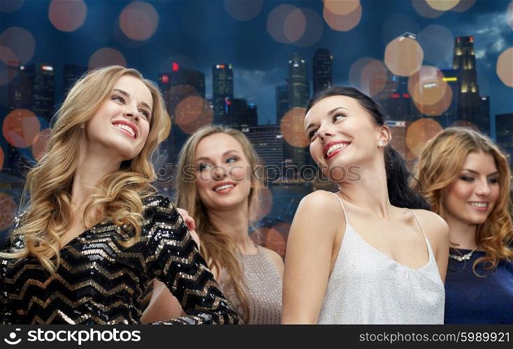party, holidays, nightlife and people concept - happy young women dancing at night club disco over city and lights background