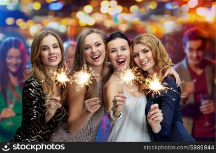 party, holidays, nightlife and people concept - happy young women with sparklers at night club over lights background