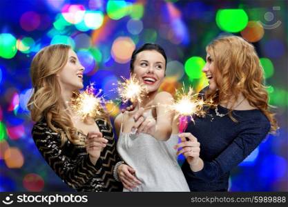 party, holidays, nightlife and people concept - happy young women with sparklers over lights background