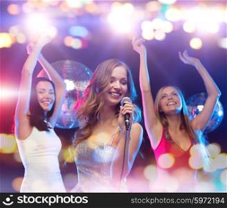 party, holidays, nightlife, entertainment and people concept - concept - happy women with microphone singing karaoke and dancing at night club