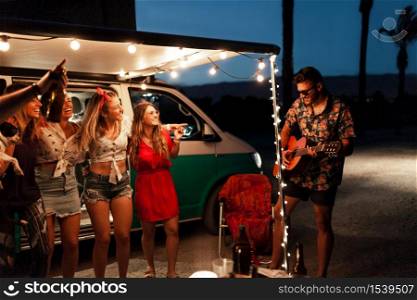 Party men are singing their friends at night near a camper van