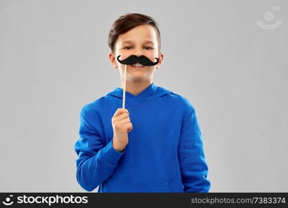 party props, photo booth and childhood concept - smiling boy in blue hoodie with black moustaches over grey background. smiling boy in blue hoodie with black moustaches