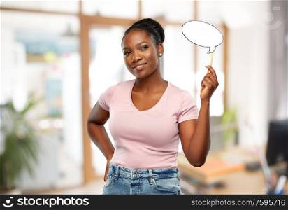 party props, photo booth and communication concept - happy african american young woman holding blank speech bubble over office background. african woman with speech bubble at office