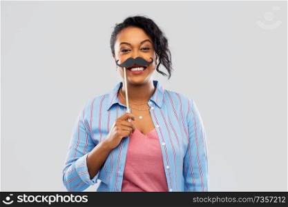 party props, photo booth and people concept - happy african american young woman with big black moustaches over grey background. african american woman with vintage moustaches