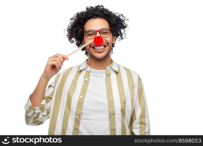 party props, photo booth and people concept - happy smiling young man with red clown nose over white background. smiling man with red clown nose party accessory