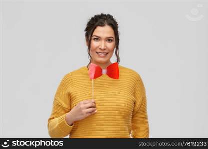 party props, photo booth and people concept - portrait of happy smiling young woman with pierced nose big red bowtie over grey background. happy young woman with big red bowtie party prop