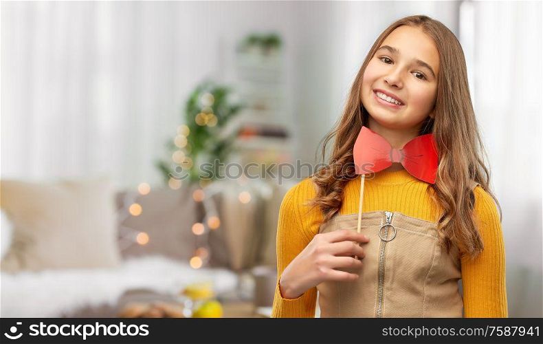 party props, photo booth and people concept - smiling teenage girl with big red bowtie over home background. happy teenage girl with red bowtie party accessory