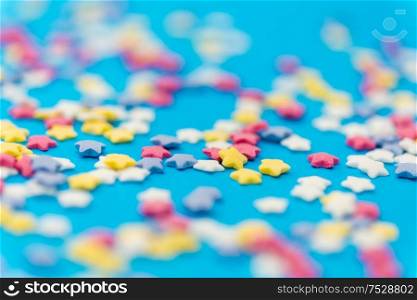 party, sweets and decoration concept - star shaped sugar sprinkles on blue background. star shaped pastry sprinkles on blue background